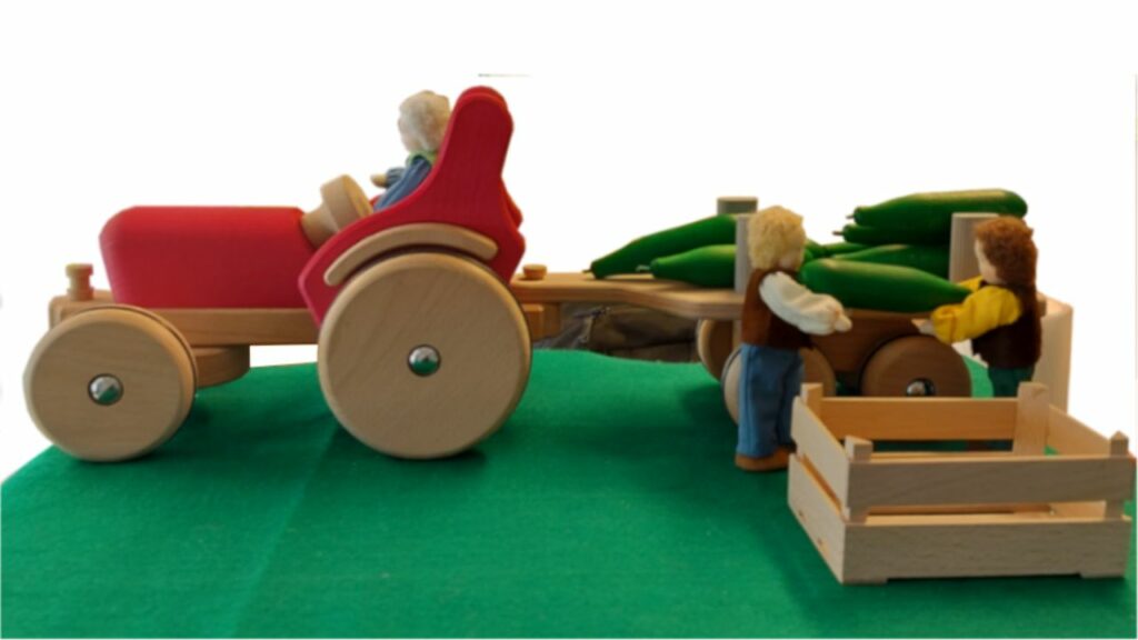 Children’s wooden toy tractor with a trailer loaded with vegetables.
