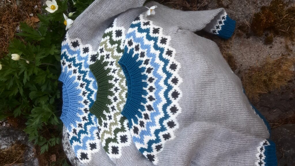 Hand-knitted sweaters featuring patterned collars and decorative sleeves.